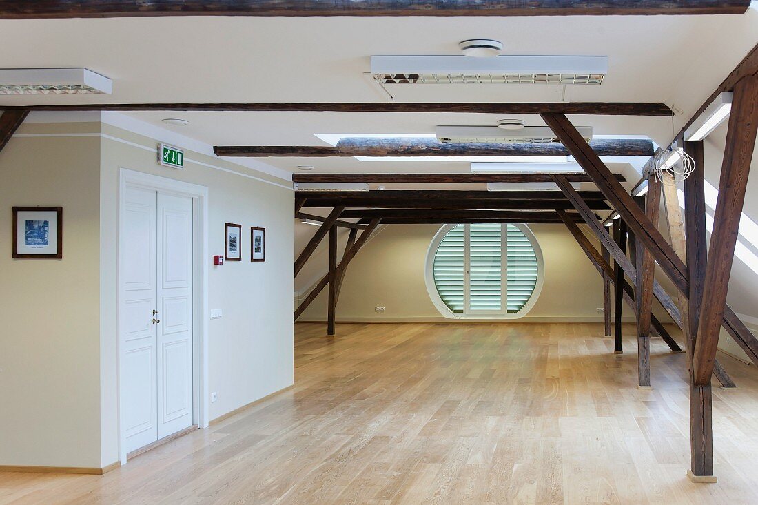 Ein leerer Raum mit Holzstützen und rundem Fenster