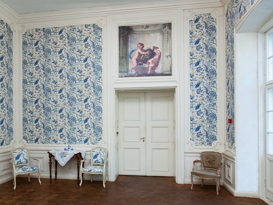 Elegantes Zimmer mit blau-weiss gemusterter Tapete und weisser Holzverkleidung