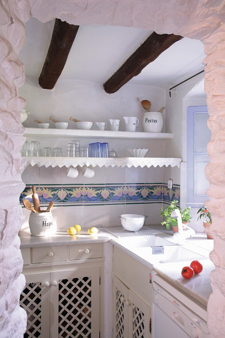 Nostalgisch angehauchte mediterrane Küche mit Holzschränkchen und Wandboards mit Spitzenbordüre