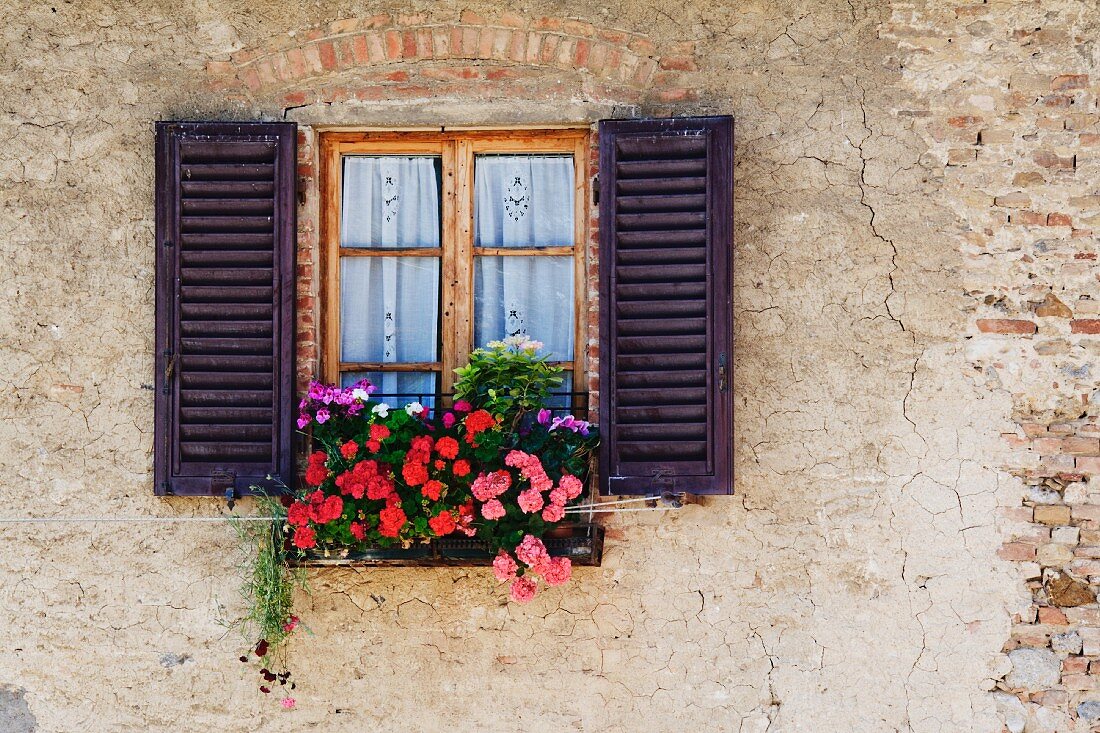 Rustikale Fassade mit blumenbewachsenem Fenster