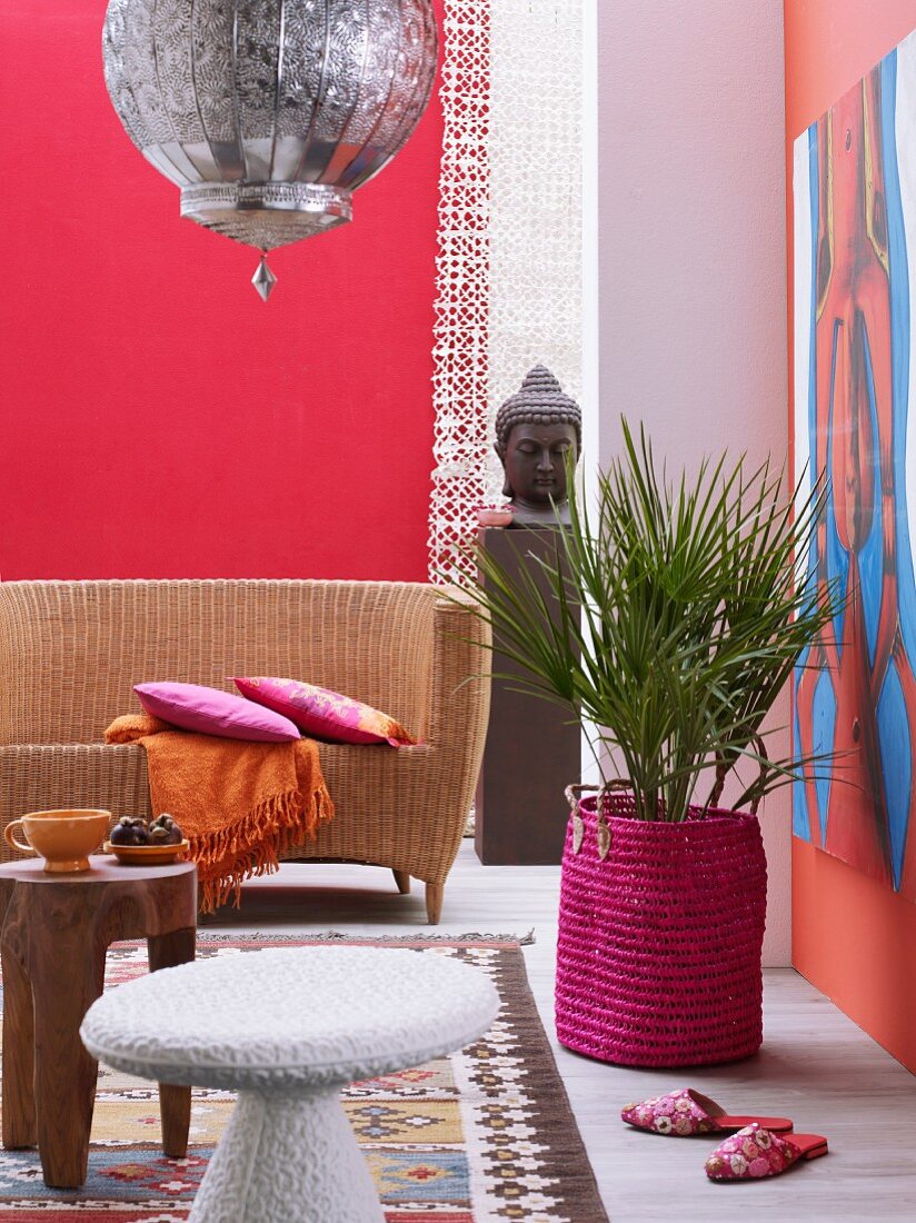 Ethnic shades of magenta and red in pleasant interior with wicker sofa
