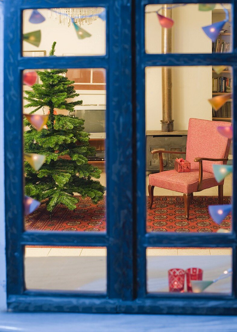 Blick durch das Fenster in ein Wohnzimmer mit Weihnachtsbaum