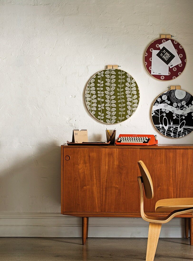 Retro-patterned plates hanging on wall above fifties-style wooden sideboard