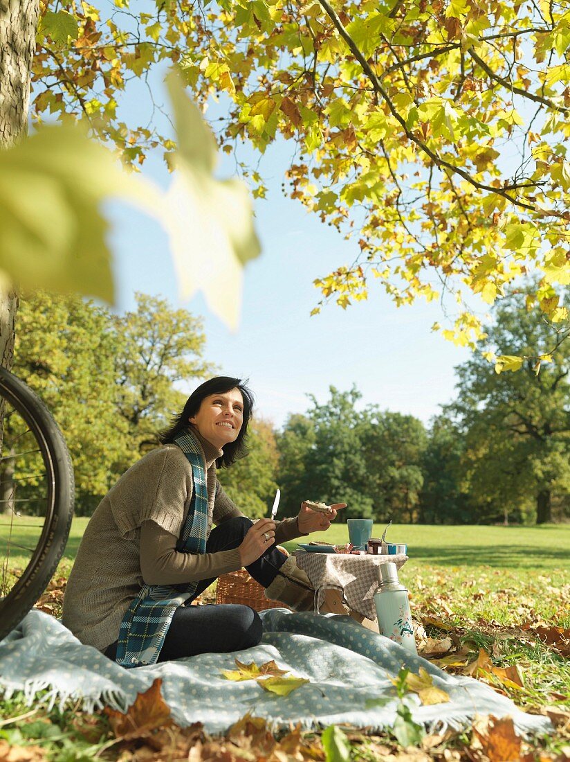 Frau geniesst herbstliches Picknick unter Baum