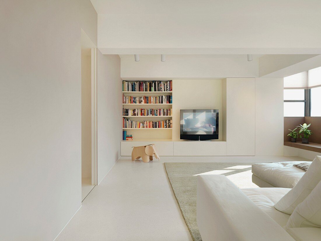 Minimalistisches Wohnzimmer in Weiß mit Einbauregal und integriertem Fernseher