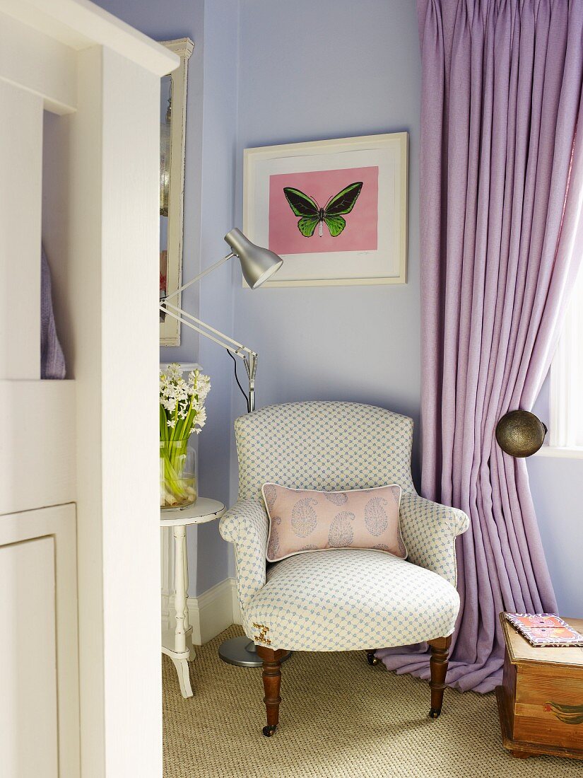 Antiker Sessel und moderne Stehlampe in fliederfarbener Zimmerecke neben bodenlangem Vorhang am Fenster
