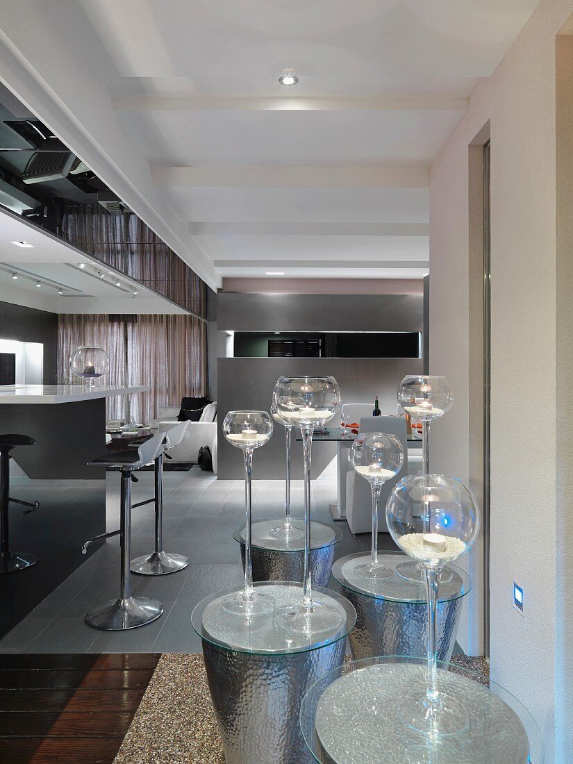 Windlichter in eleganten Kerzenhaltern aus Glas auf Beistelltischen aus punziertem Metall in modernem Wohnzimmer