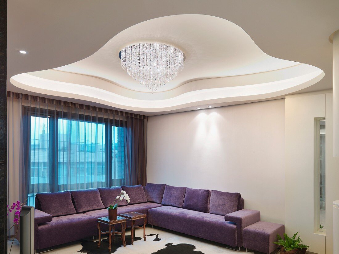 Futuristic ceiling design with modern chandelier above a corner sofa at a window