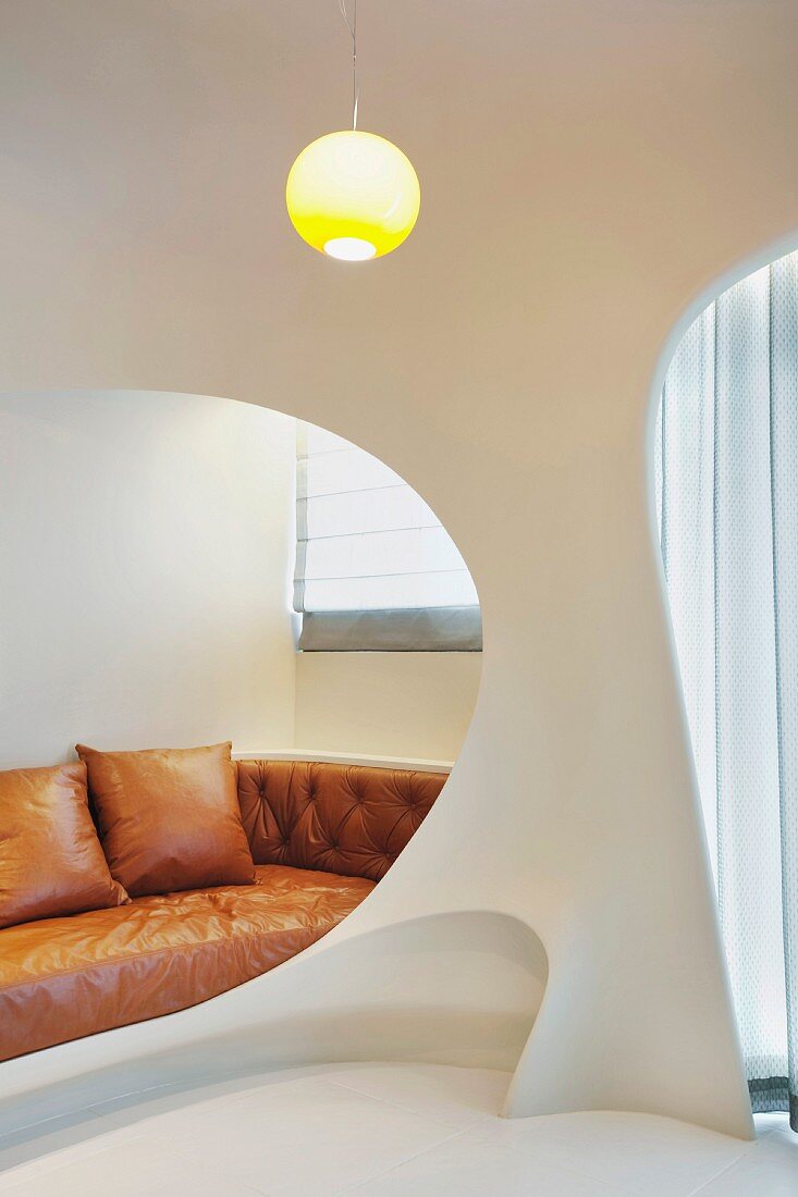 Futuristischer Raumeinbau mit Öffnungen und Blick auf lederbezogenes Sofa in Hellbraun