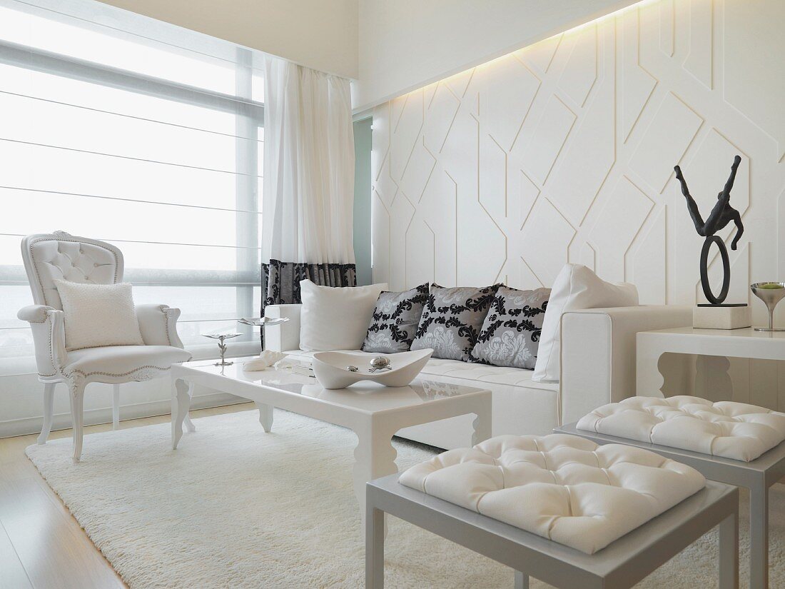 Wohnzimmer mit postmodernen Hockern vor Couchtisch und neobarocker Sessel in Weiß