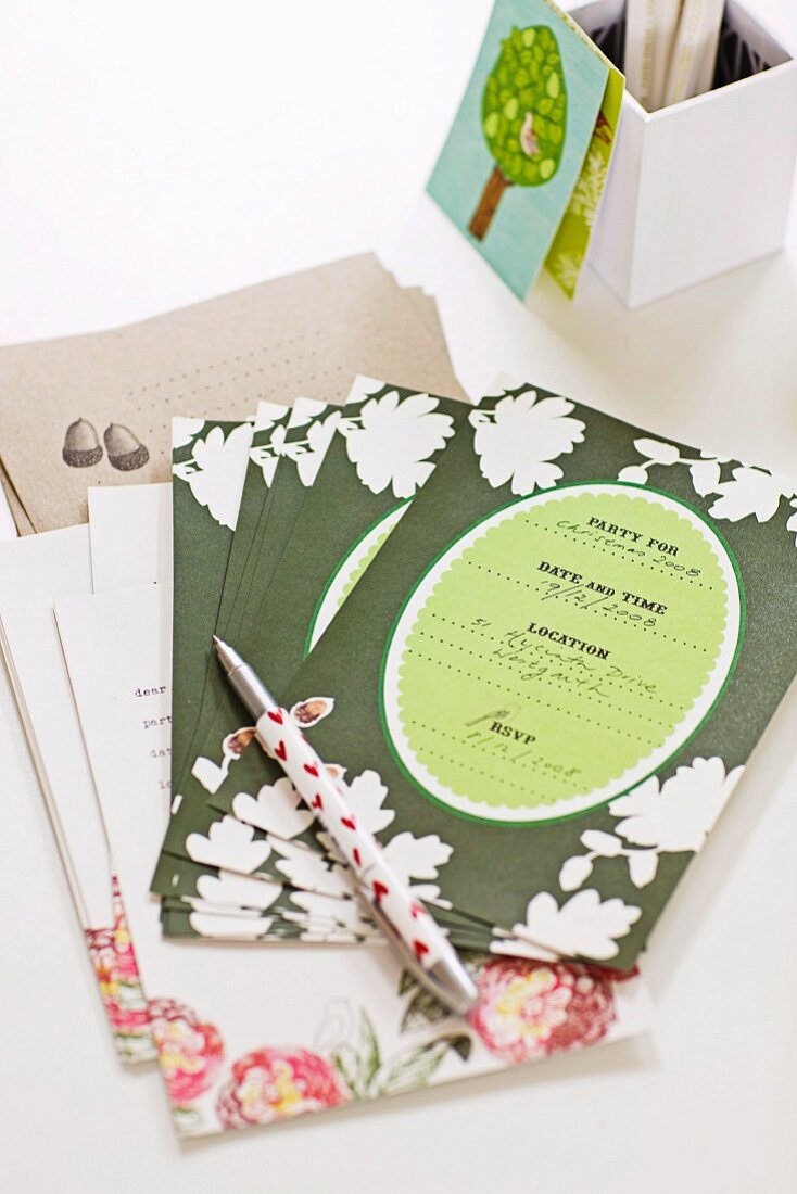 Invitation cards and pen in front of white cardboard storage box