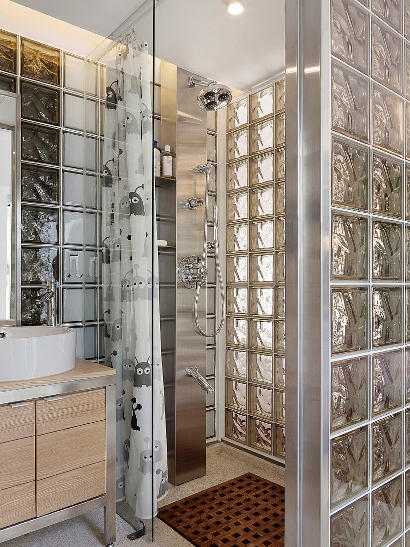 Eine Edelstahlduschsäule im bodengleichen Duschbereich mit Glasbausteinwänden