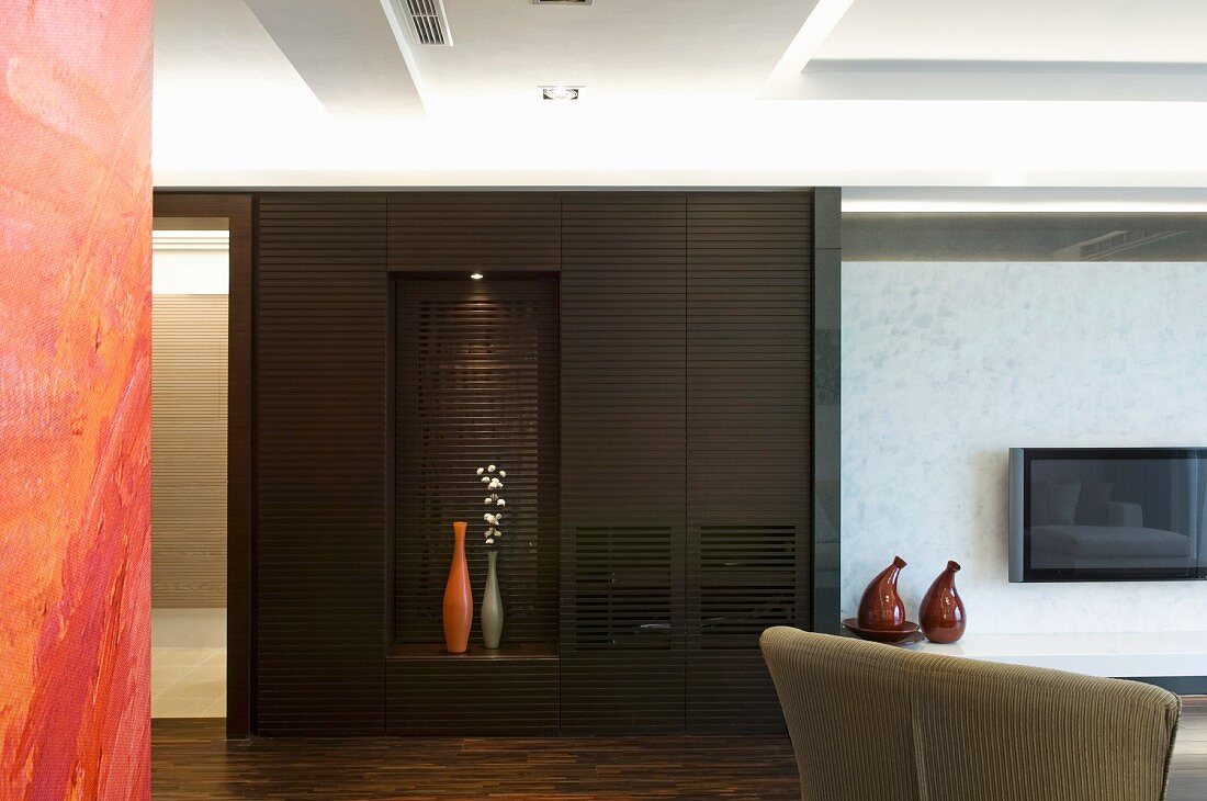 A dark built-in cupboard with illuminated niche for decorative vases