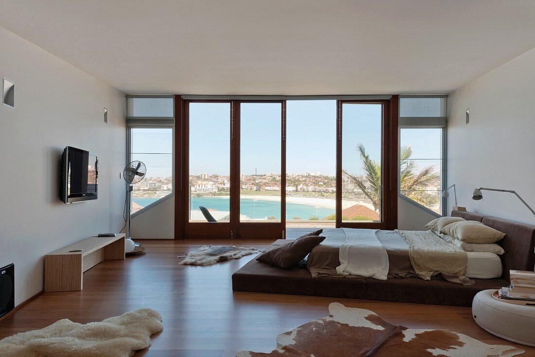 A platform bed in a modern living-bedroom area with a view of the beach