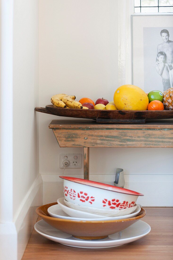 Various bowls and dishes in front of full fruit bowl on old wooden bench