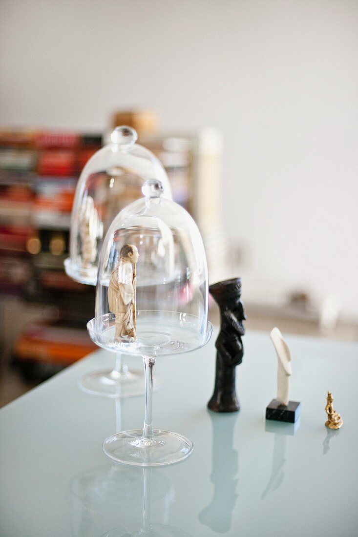 Small figurines and bell jars on a glass table