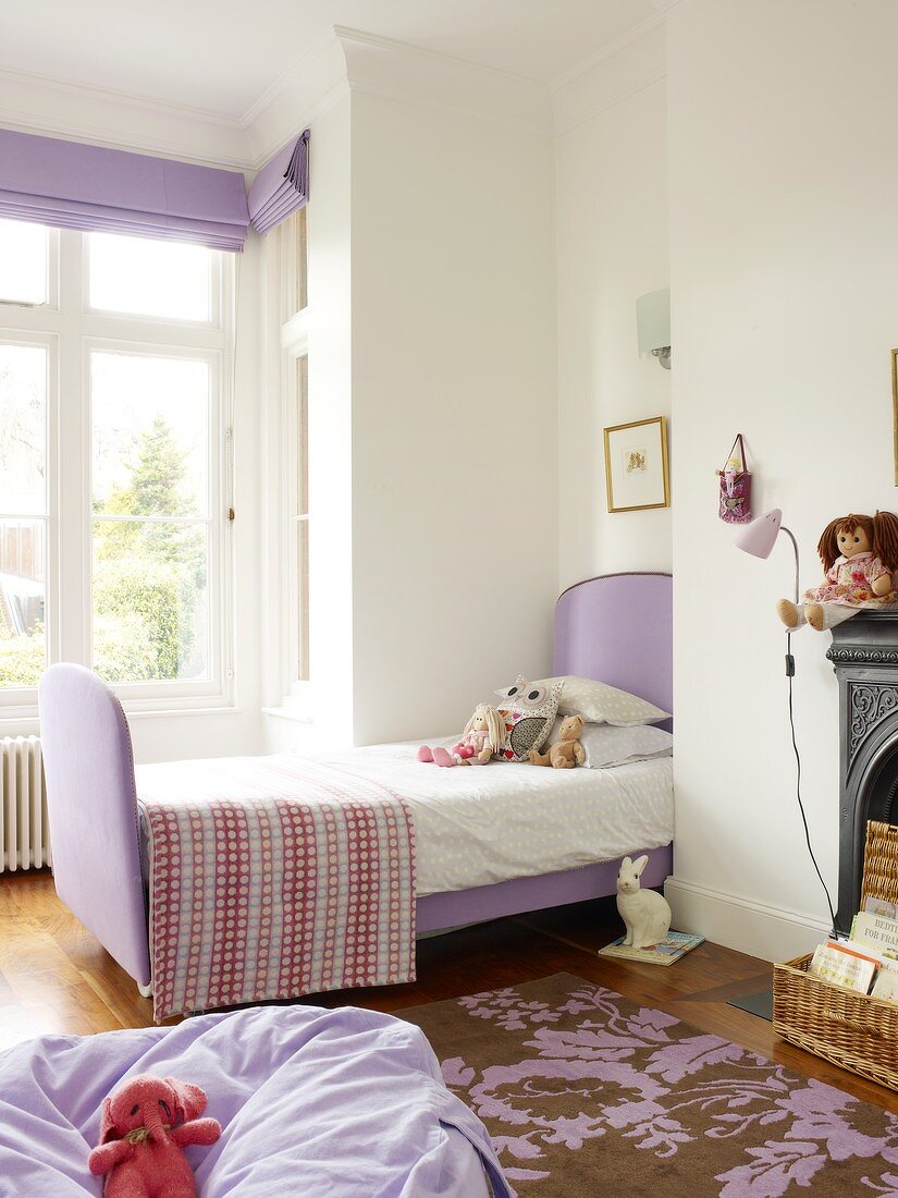 Violetter Sitzsack auf gemustertem Teppich und Schlittenbett mit violettem Stoffbezug vor Erker im Kinderzimmer