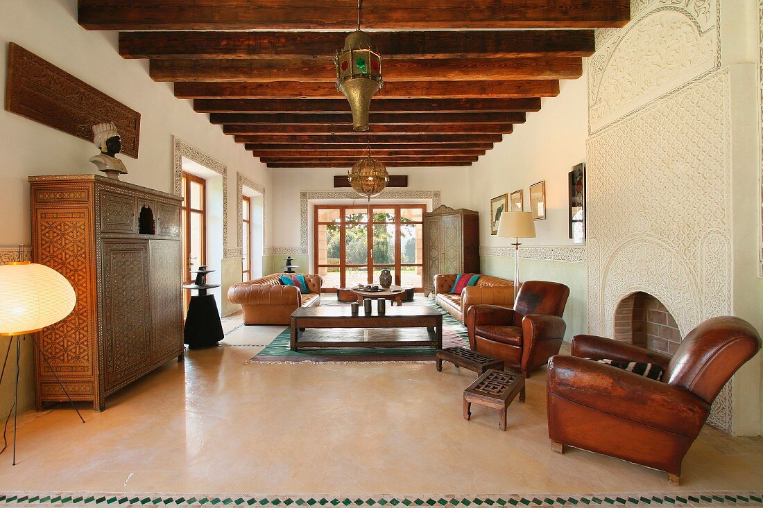 Alte Ledersessel und Holzschränke in einer spanischen Villa mit rustikaler Holzbalkendecke