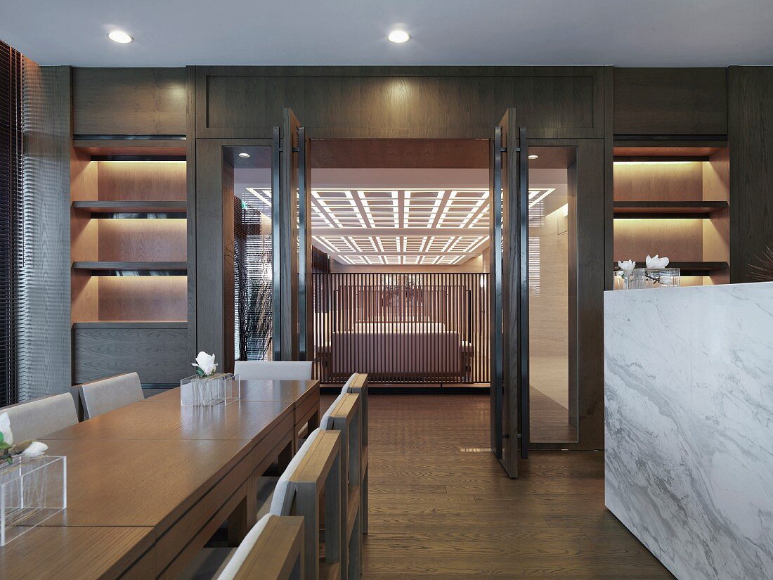 Moderner Esstisch aus hellem Holz und Blick durch offene Tür in Designer Wohnraum