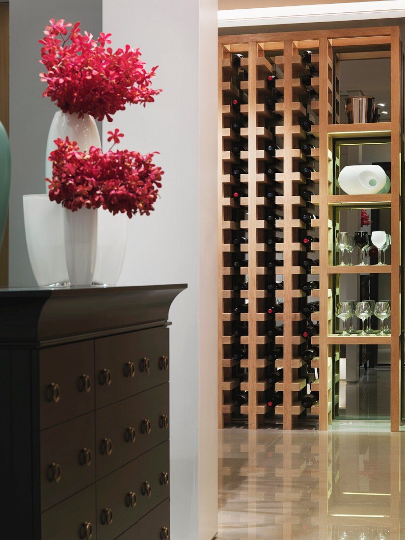 Blumenvase auf Kommode im Vorraum und Blick auf modernes Weinregal als Raumteiler