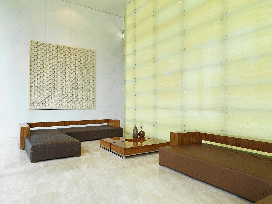 Elegante Polstersofa mit Holzablage vor Raumteiler aus Glas und integrierter Beleuchtung
