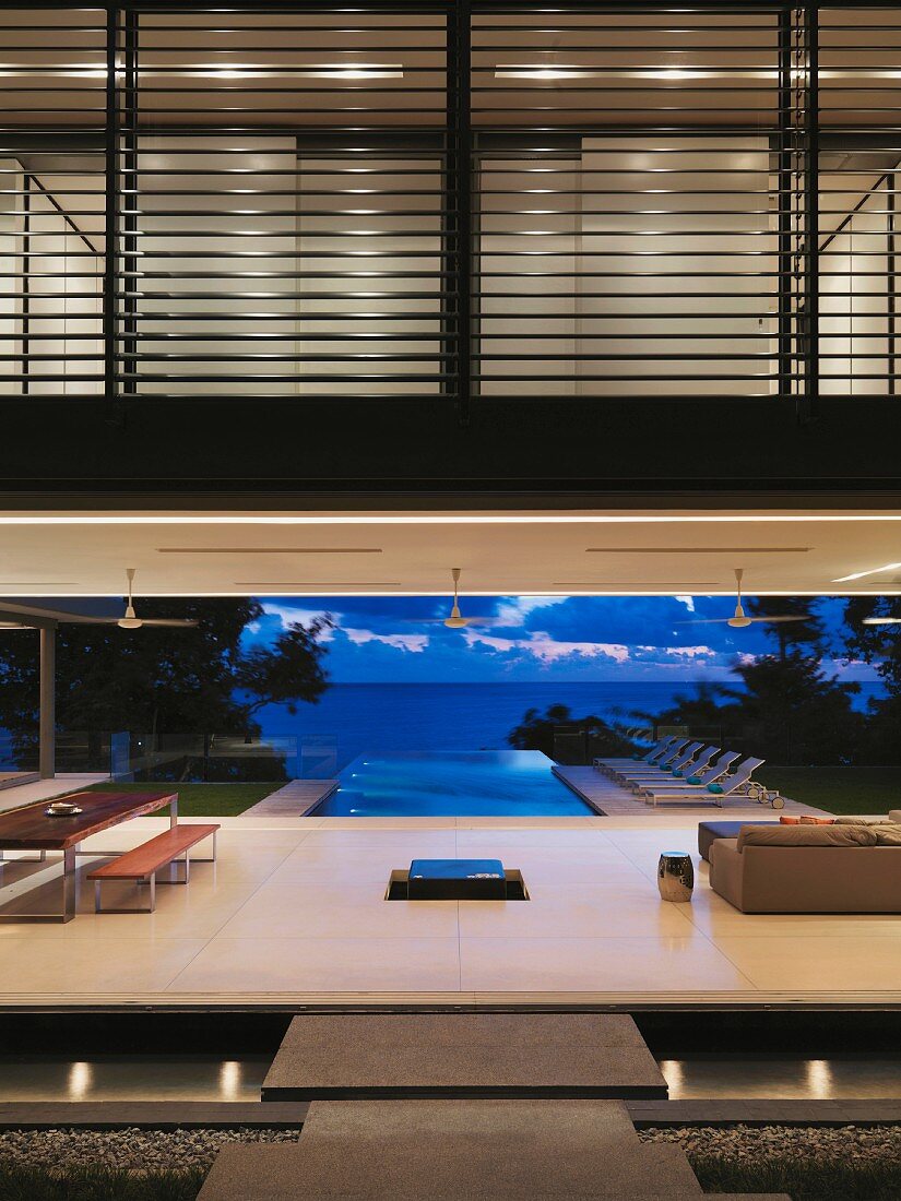 Modern home with pool and ocean view at dusk