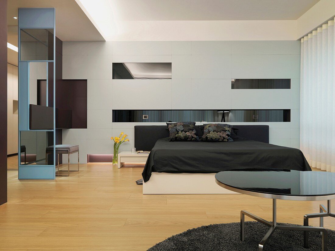 Spiel mit geometrischen, dunklen Glasflächen im modernen Schlafraum mit schwarzweissem Doppelbett