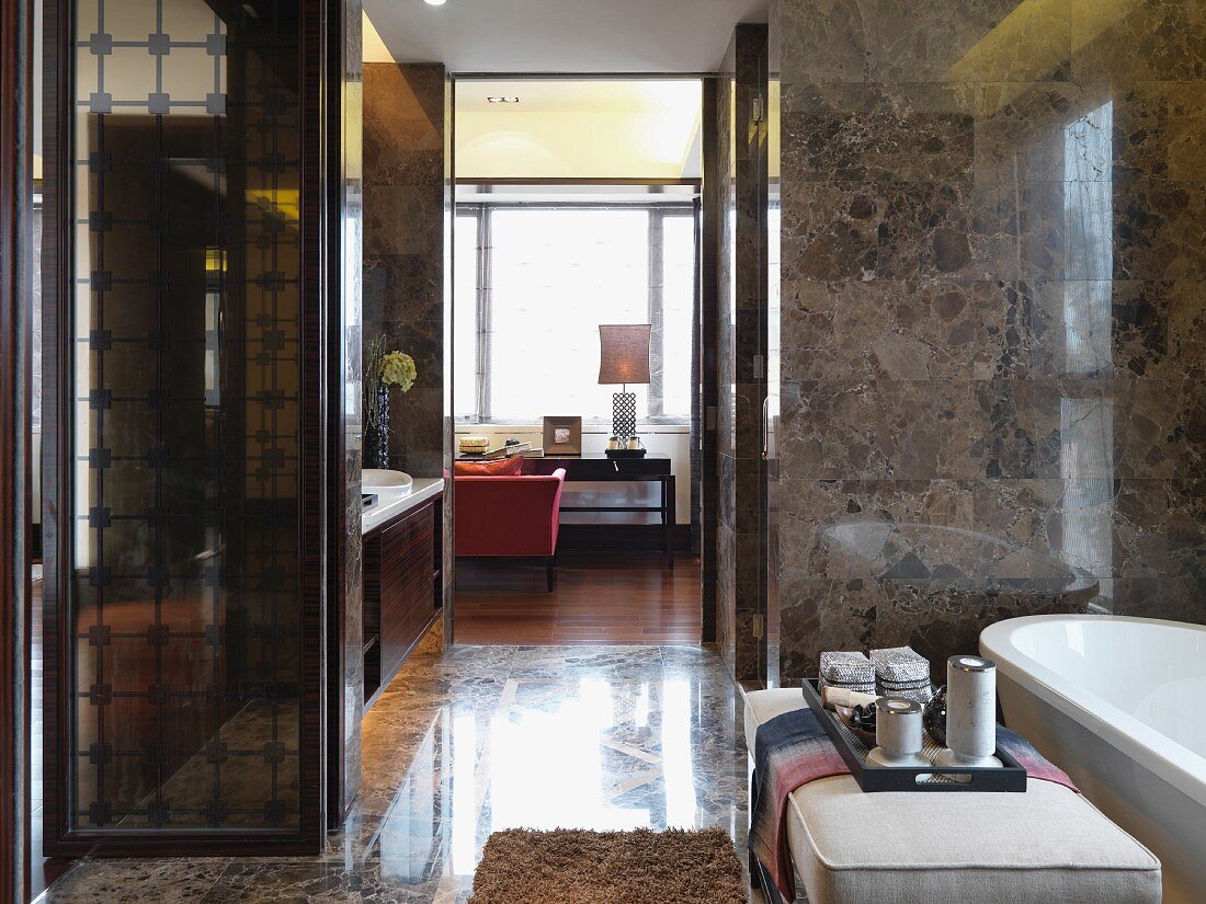 Blick vom marmorverkleideten Badezimmer auf eleganten Schreibplatz im Schlafzimmer