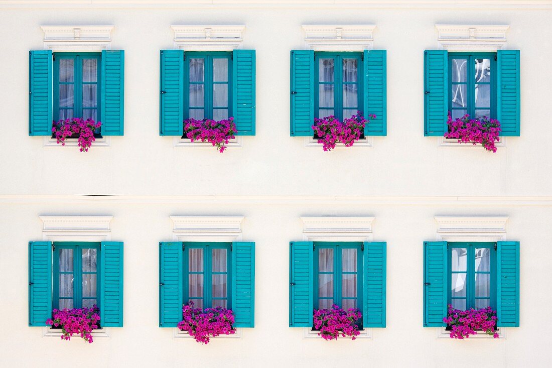 Blaue Fenster mit Fensterläden und Blumenkästen