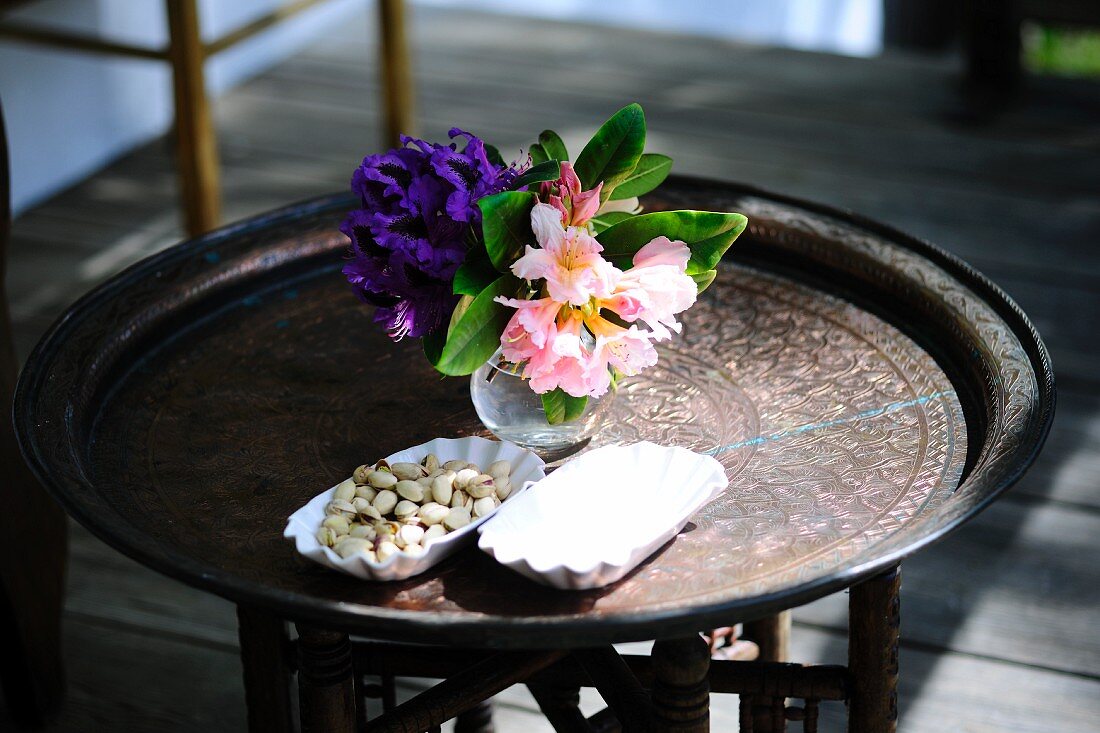 Pistachios and a vase of flowers on a side table