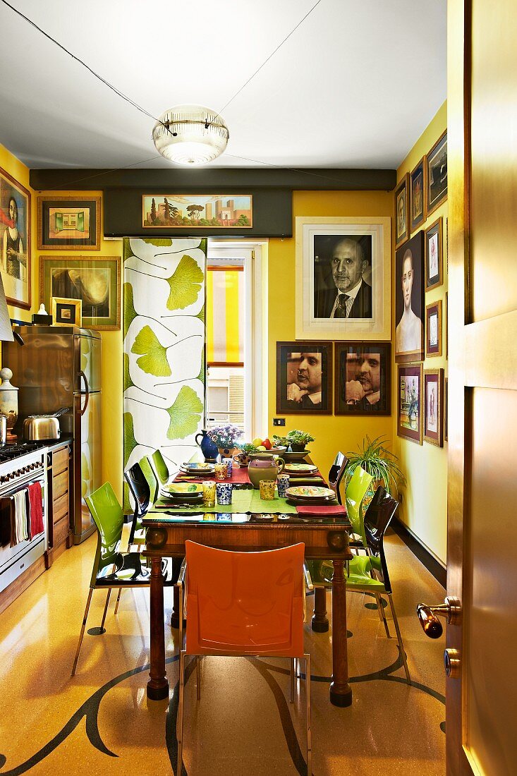 Sonnige Küche in Gelb mit antikem Esstisch, Portraitfotos an der Wand und einem Vorhang mit Gingkoblättermuster