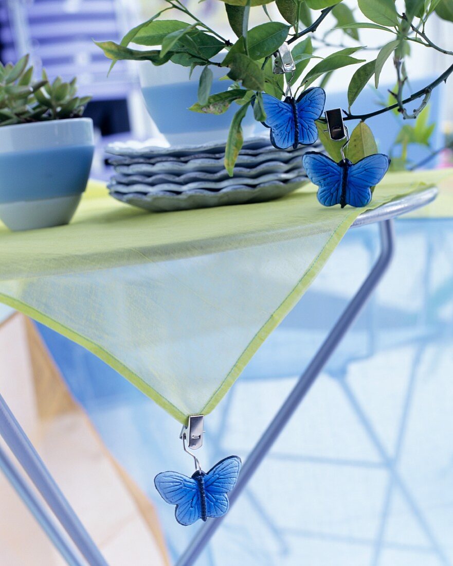 Deko-Schmetterlinge an Tischdecke und Bäumchen geklipst