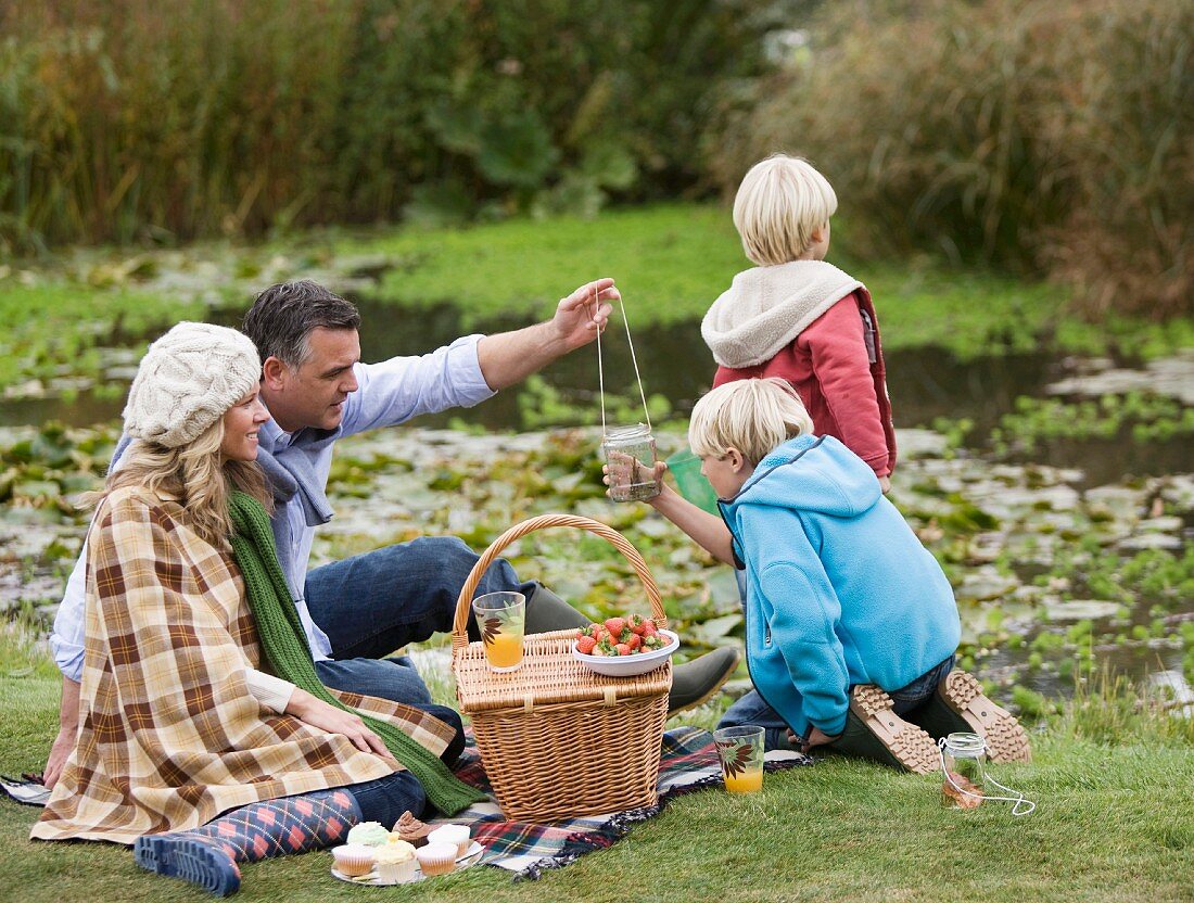 Familie beim Picknick an kleinem Teich im Herbst