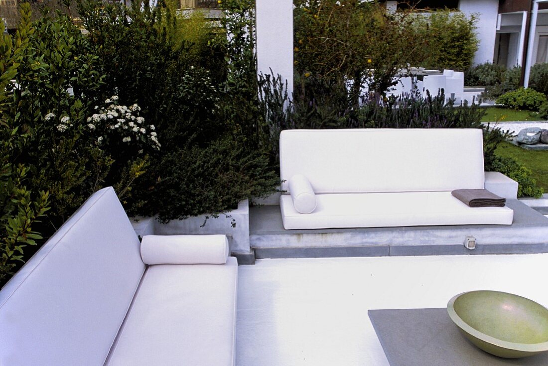 Sitzecke mit weissen Sofas & Tisch im Garten