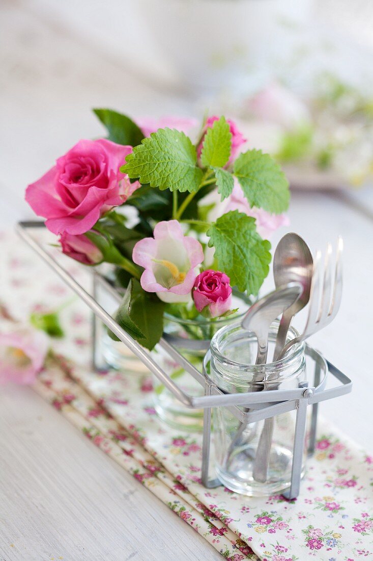 Tischdekoration mit pinkfarbenen Rosen, Glockenblumen und Zitronenmelisse