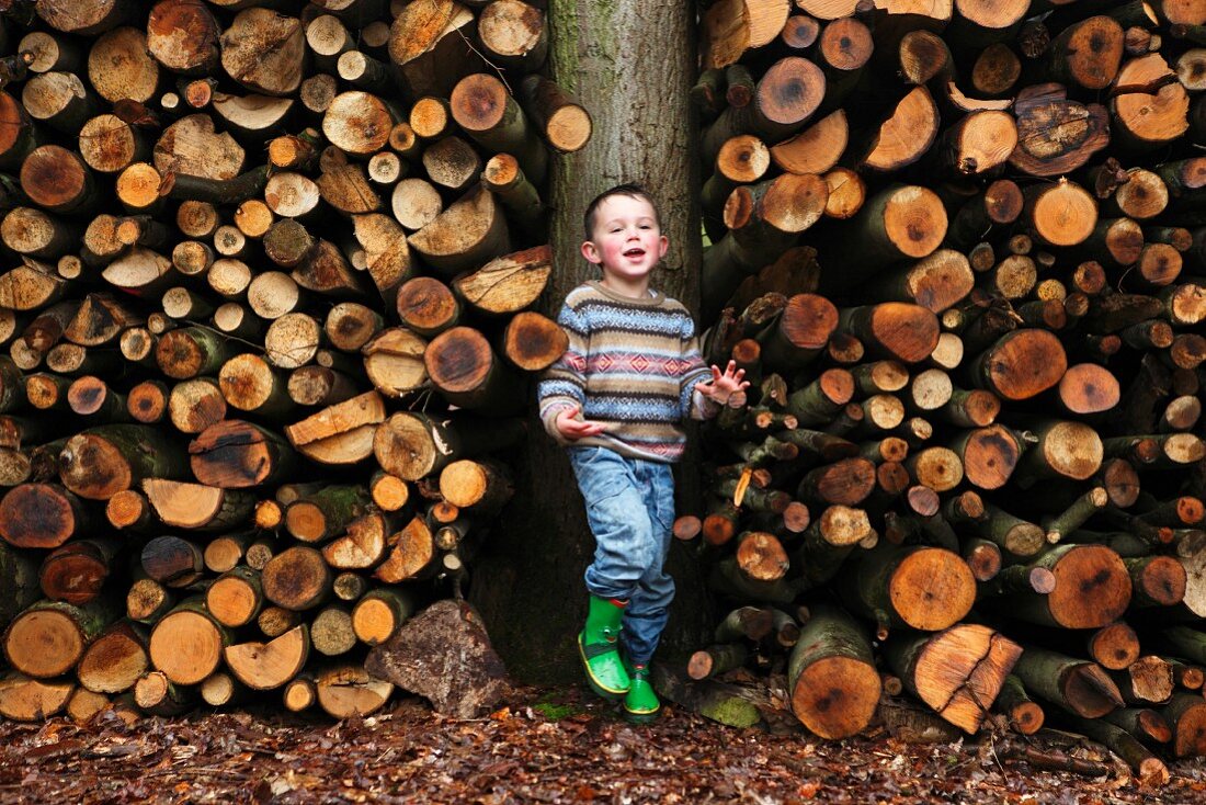 Kleiner Junge steht vor Holzstapel