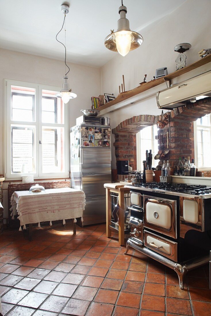 Country house with old kitchen cooker in front of brick archways and terracotta floor tiles