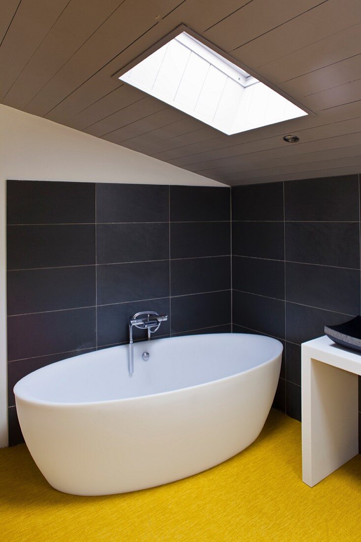 Minimalist bath tub under a pitched roof with skylight