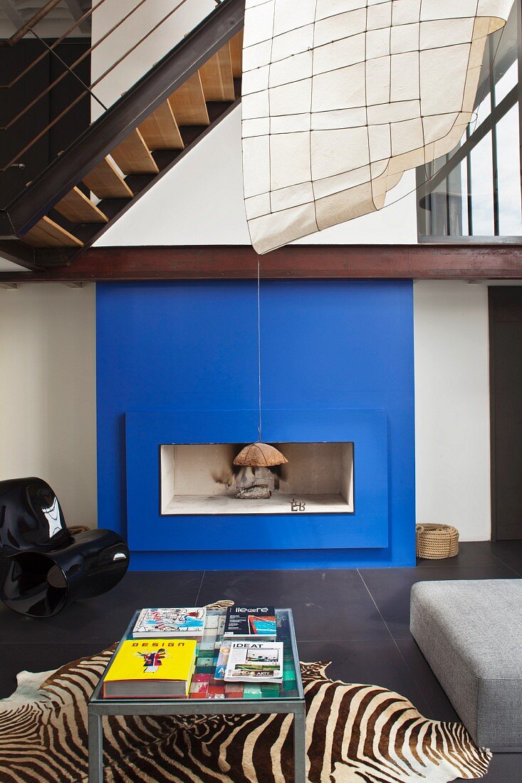 Ein tiefblauer Kamin und ein Zebrateppich sind der Blickfang dieses modernen Wohnzimmers