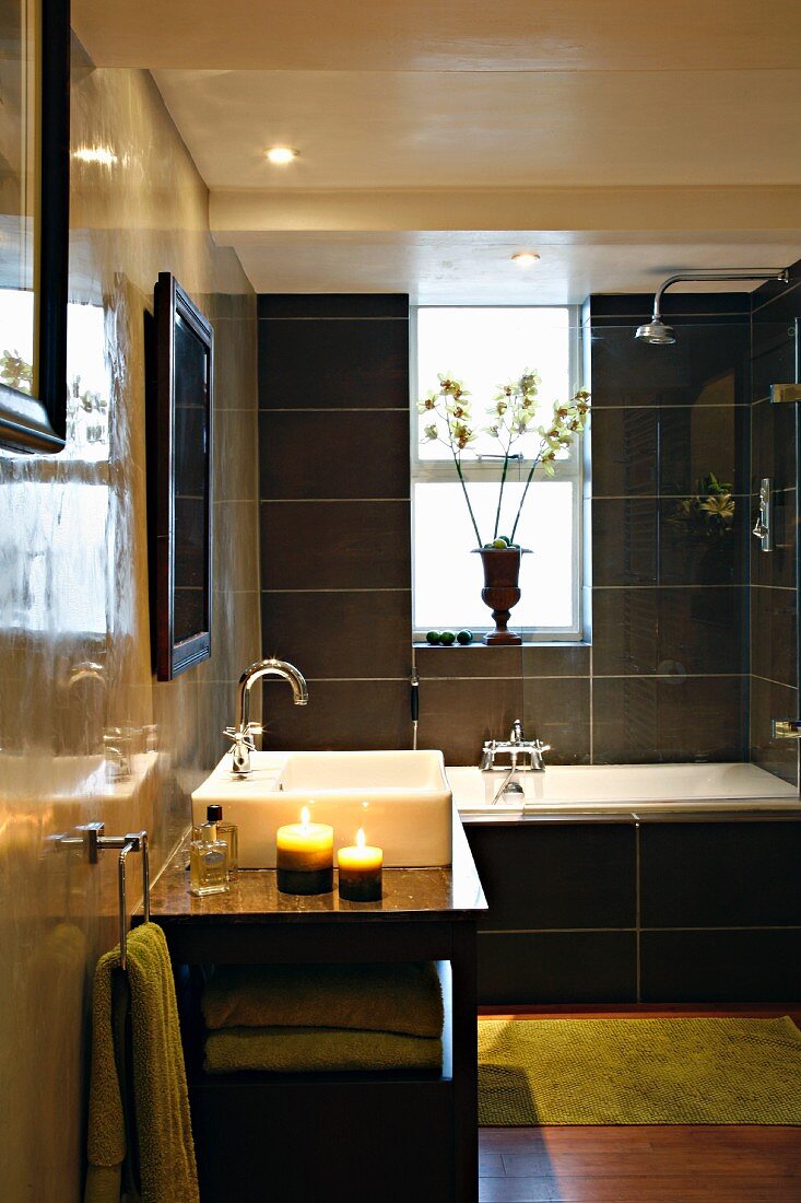 Polierte Wände und schwarze Fliesen im Badezimmer mit Badewanne und Waschbecken