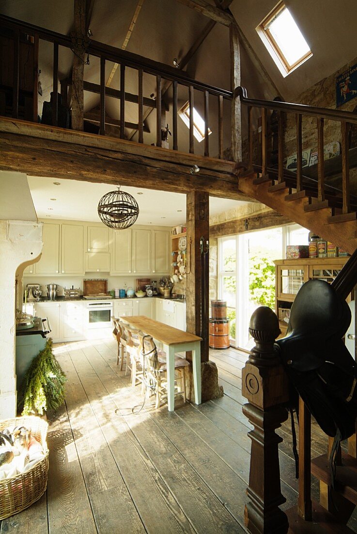 Offener Wohn-Essbereich im Landhausstil mit rustikalem Dielenboden und Holztreppe zur Galerie