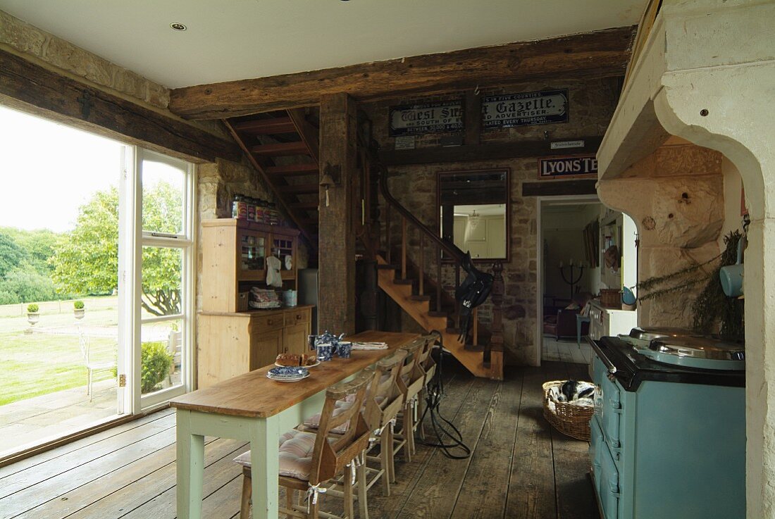 Offener Wohn-Essbereich im Landhausstil mit rustikalem Dielenboden und Holztreppe zur Galerie, Fensterfront zum Garten ist geöffnet