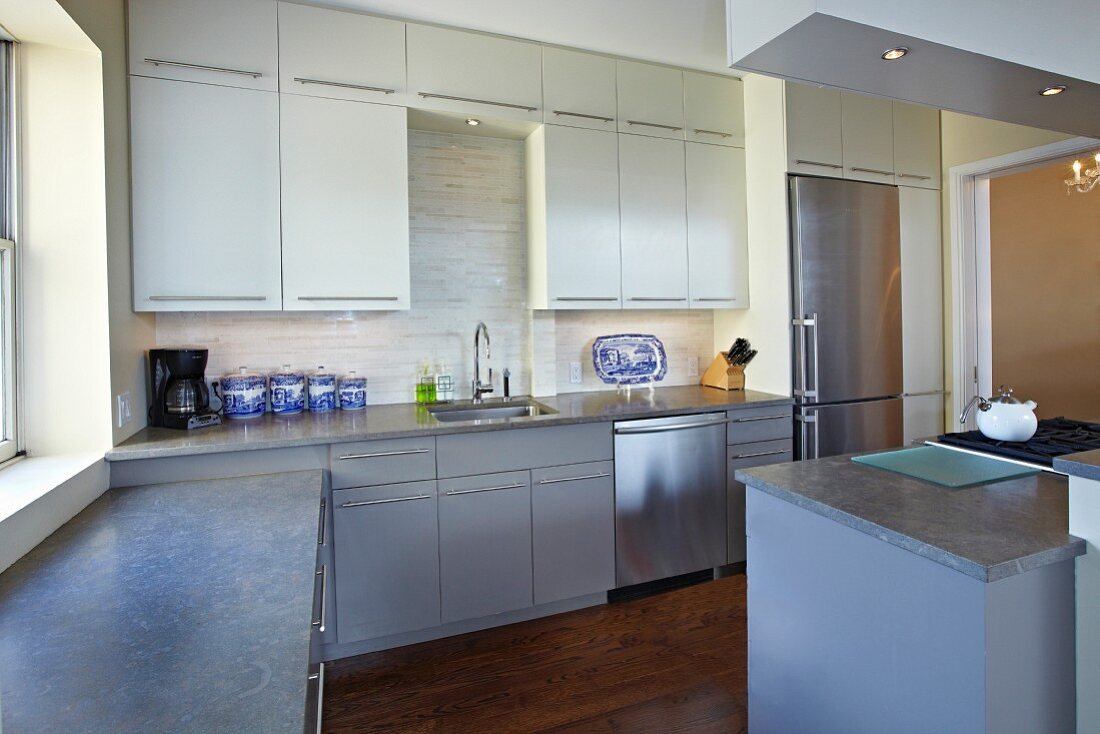 Moderne, graue Küchenzeile mit weissen Oberschränken und Edelstahlgeräten
