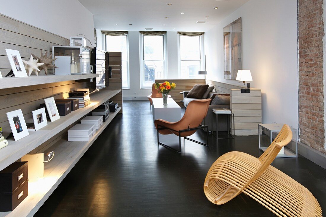 Origineller Designerstuhl aus gebogenen Holzstäben in einem modernen Wohnzimmer mit langem Wandregal und Fensterfront