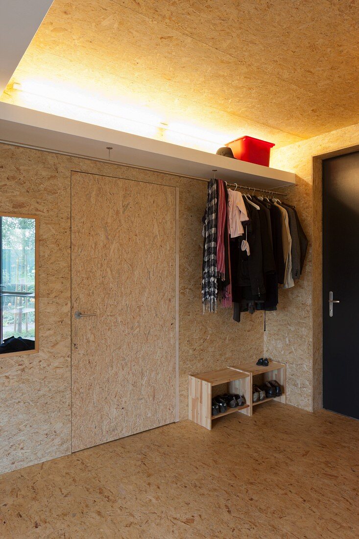 Offene Garderobe im Vorraum mit Spanplattenausbau und indirekter Deckenbeleuchtung