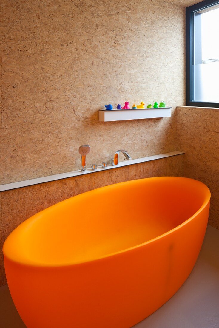 Freistehende Badewanne in Orange in Badezimmer mit Spanplattenausbau