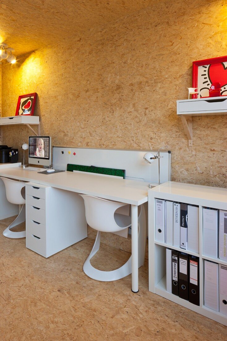 Arbeitstisch an Wand in Weiß mit Designer Schalenstühlen in Raum mit Spanplatten