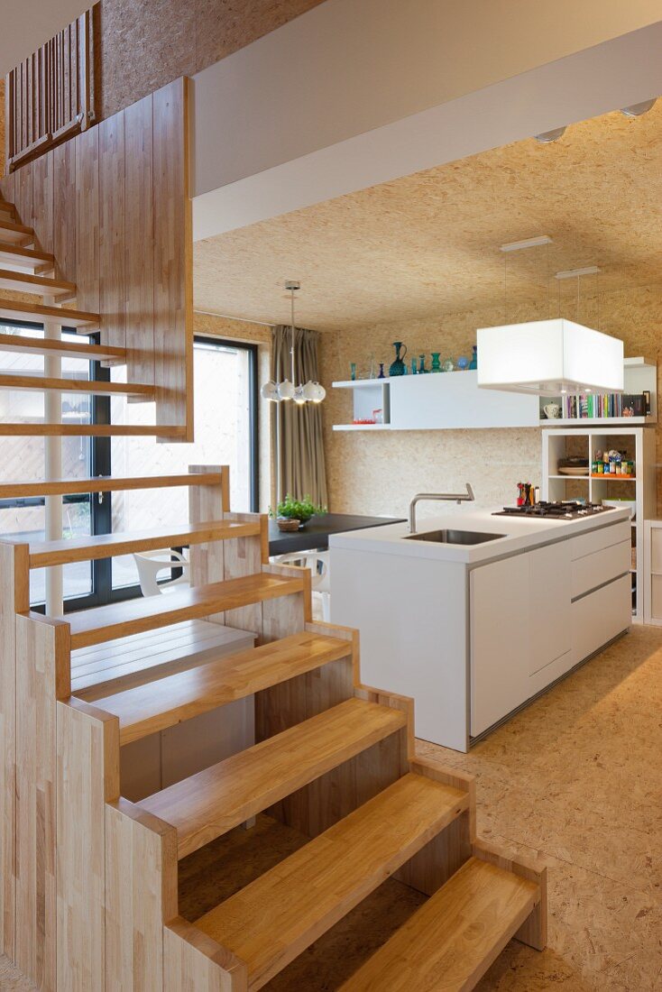 Modern, wooden staircase in open interior with view of kitchen counter