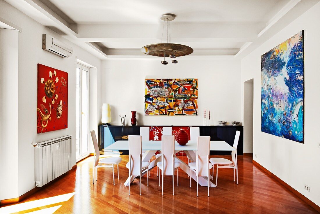 Expressionistische Gemälde rahmen den modernen Esstisch mit Designerstühlen optisch ein