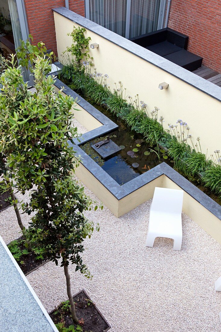 Geometric garden with square beds and elongated pool along garden wall